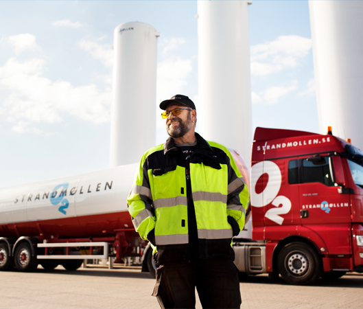 Glad og produktiv Strandmøllen medarbejder, foran lastbil, og gastanke. Arbejder i gas industri. 
